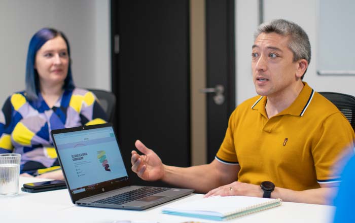 Man on a laptop talking to room of people